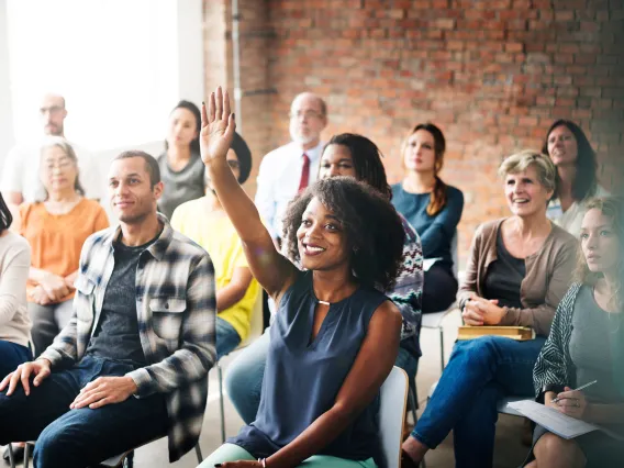 Group of people in class, some raising hands