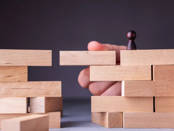 Wooden blocks, hand holding a block so wood person can cross over