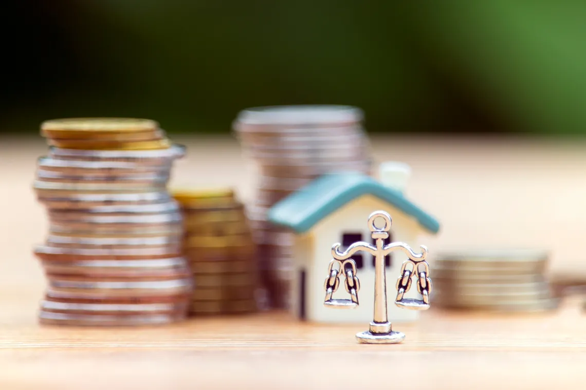 Justice scale, house and coins stacked in background