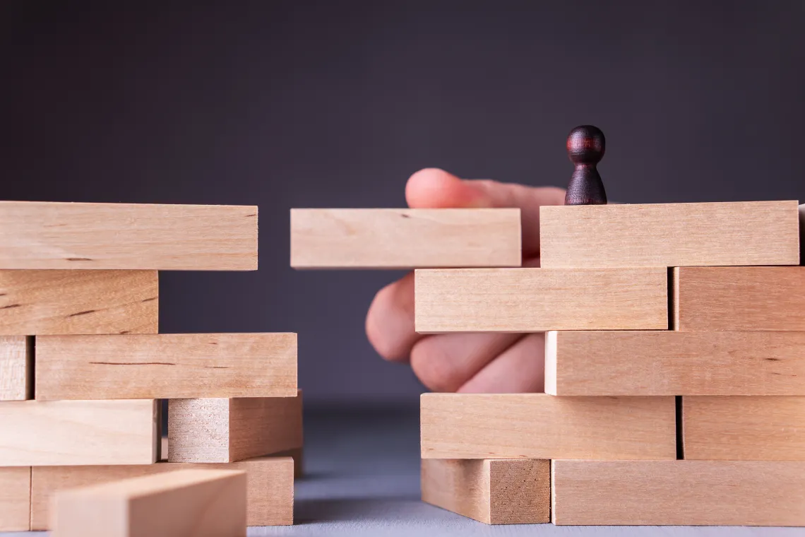 Wooden blocks, hand holding a block so wood person can cross over